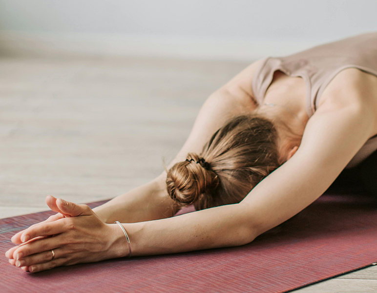 chica estirando en suelo con las palmas cerradas practicando yoga